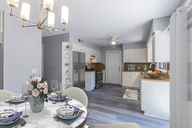 kitchen with dark wood-style flooring, a sink, decorative backsplash, stainless steel appliances, and white cabinetry