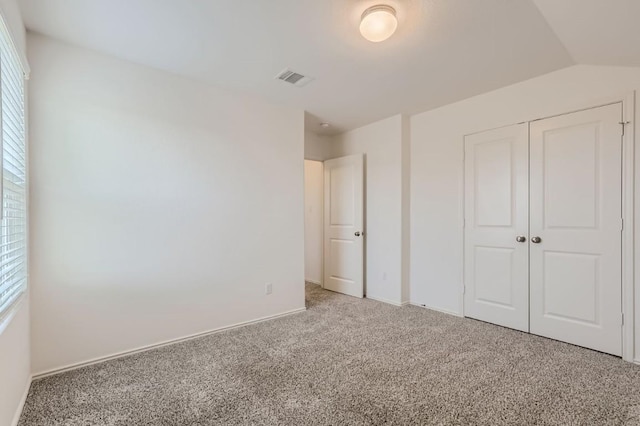 unfurnished bedroom with carpet flooring, a closet, and lofted ceiling