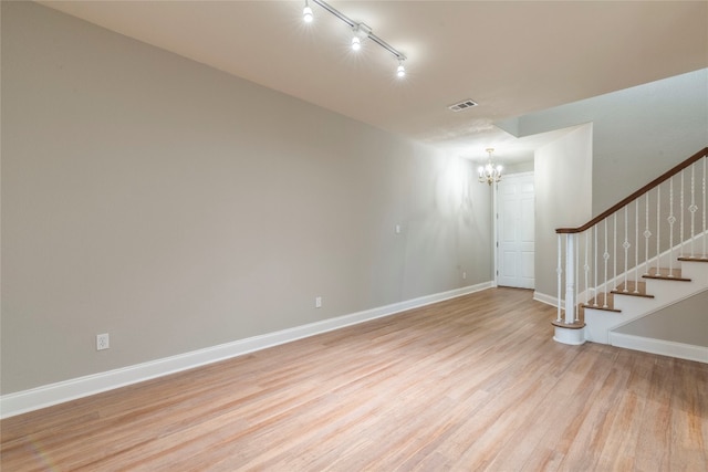 interior space with rail lighting, a chandelier, and light hardwood / wood-style floors