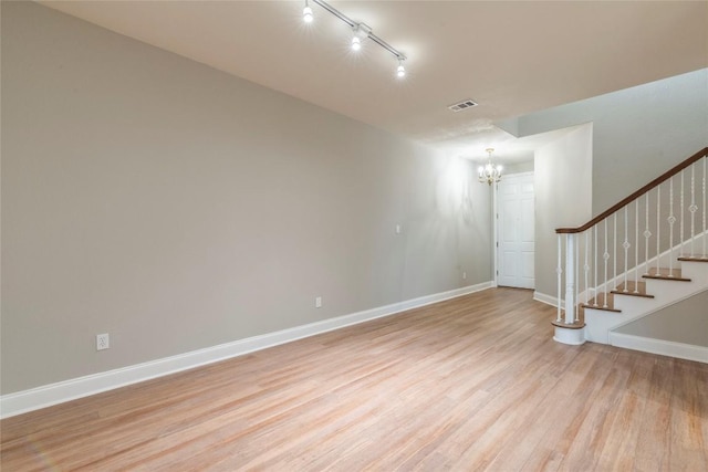 unfurnished room with a notable chandelier, visible vents, baseboards, stairs, and light wood finished floors