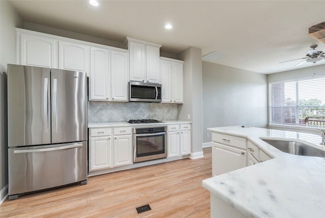 kitchen with ceiling fan, white cabinetry, appliances with stainless steel finishes, light hardwood / wood-style floors, and tasteful backsplash