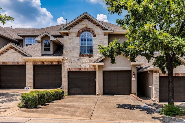 french country style house featuring roof with shingles, stucco siding, a garage, stone siding, and driveway