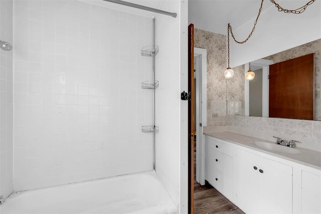 bathroom with hardwood / wood-style floors, vanity, and tiled shower / bath