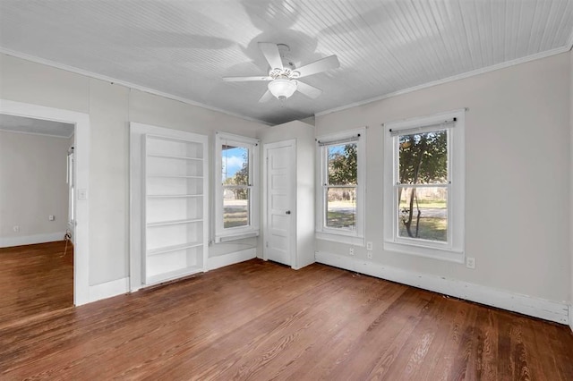 spare room featuring hardwood / wood-style floors, ceiling fan, built in features, and crown molding