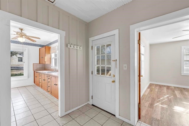 doorway to outside featuring light hardwood / wood-style flooring, ceiling fan, a healthy amount of sunlight, and sink