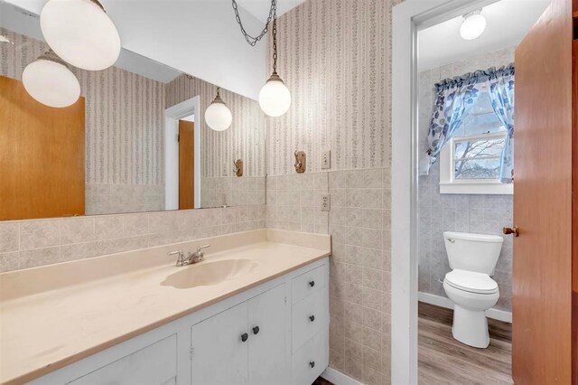 bathroom with hardwood / wood-style floors, vanity, tile walls, and toilet