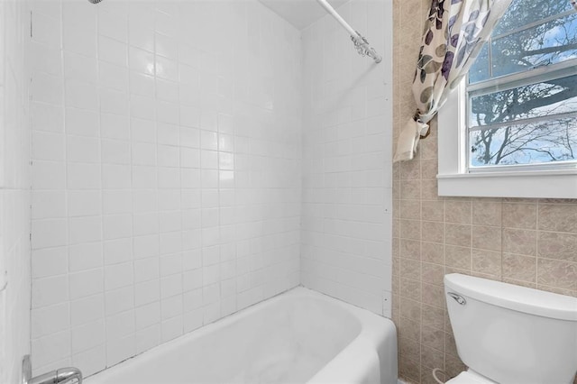 bathroom with tiled shower / bath combo, tile walls, and toilet