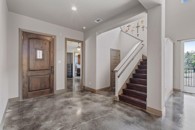 foyer entrance with ceiling fan and concrete flooring