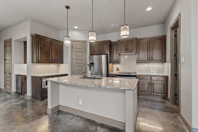 kitchen featuring dark brown cabinets, stainless steel appliances, an island with sink, sink, and decorative backsplash