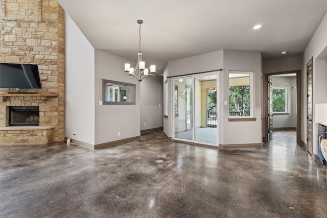 unfurnished living room with a stone fireplace and an inviting chandelier