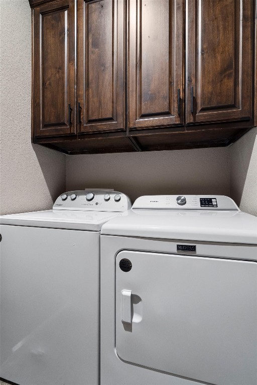 clothes washing area featuring cabinets and washer and clothes dryer