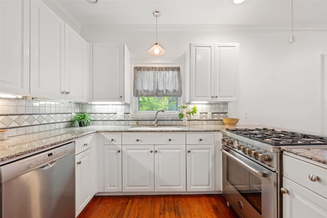 kitchen with appliances with stainless steel finishes, sink, hardwood / wood-style floors, and white cabinetry