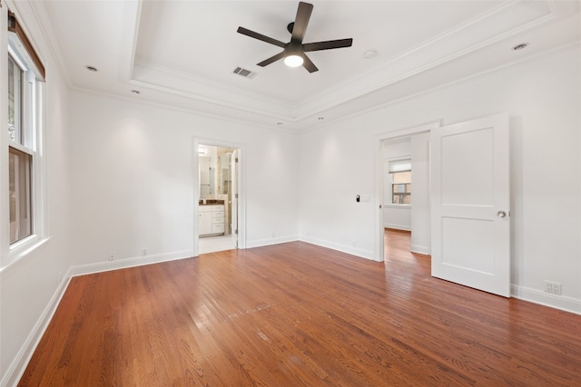 spare room featuring ceiling fan, ornamental molding, wood-type flooring, and a raised ceiling