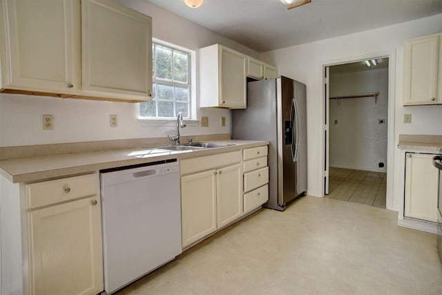 kitchen featuring stainless steel fridge, dishwasher, light countertops, cream cabinetry, and a sink