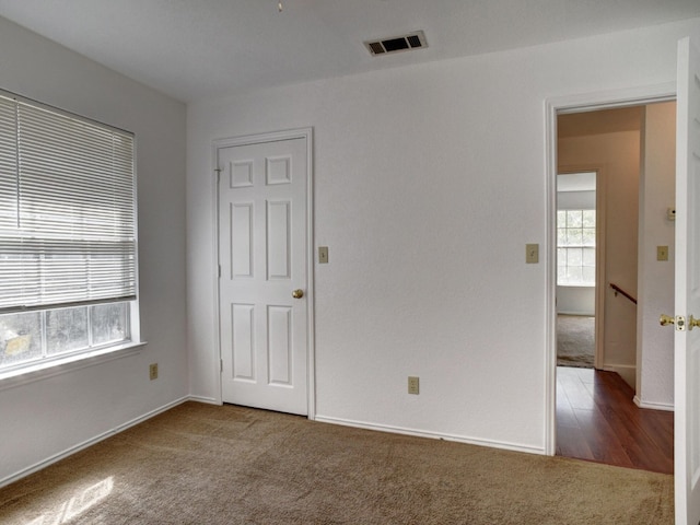 unfurnished bedroom with carpet, visible vents, and baseboards