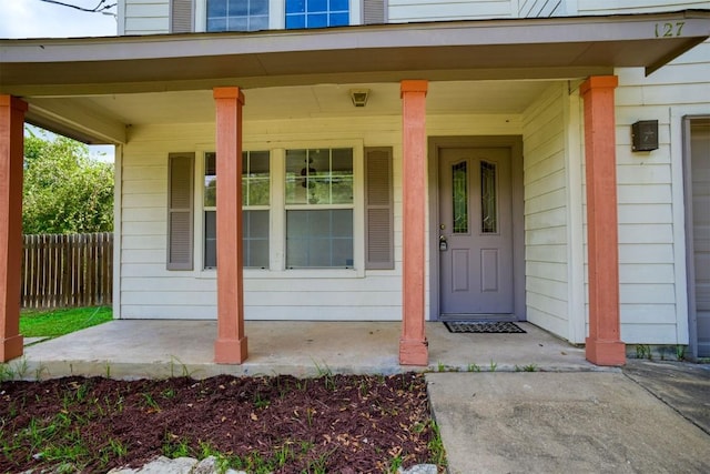 entrance to property featuring covered porch and fence