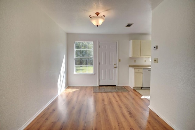 entrance foyer featuring a textured wall, light wood-style flooring, visible vents, and baseboards