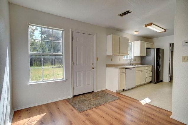 kitchen featuring light wood-type flooring, light countertops, dishwasher, and stainless steel refrigerator with ice dispenser