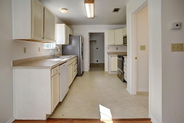 kitchen featuring light countertops, visible vents, cream cabinets, appliances with stainless steel finishes, and a sink