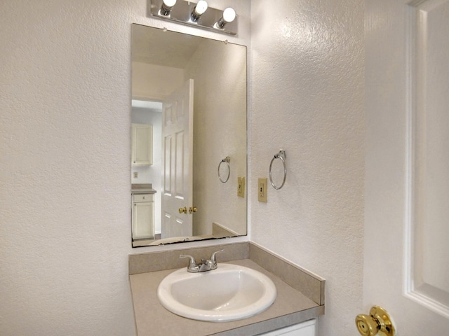 bathroom featuring a textured wall and vanity