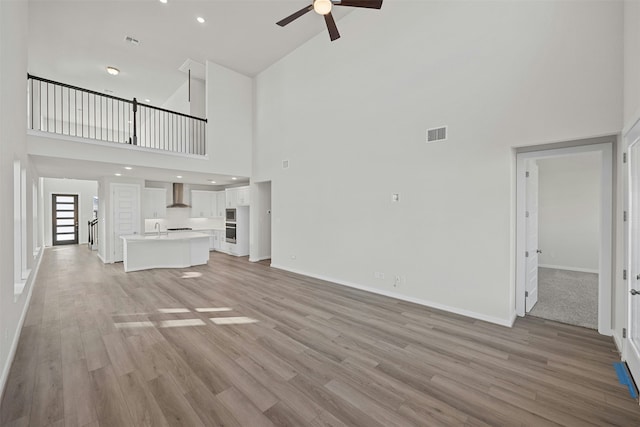 unfurnished living room featuring a towering ceiling and light hardwood / wood-style floors