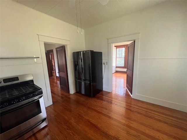 kitchen featuring black fridge, wood-type flooring, and stainless steel gas range