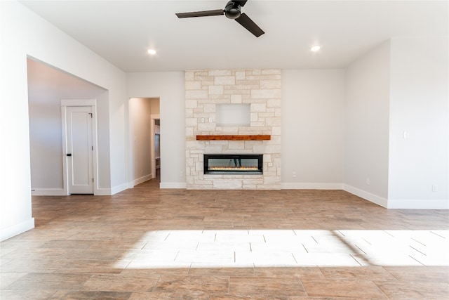 unfurnished living room with ceiling fan, a fireplace, and light hardwood / wood-style flooring