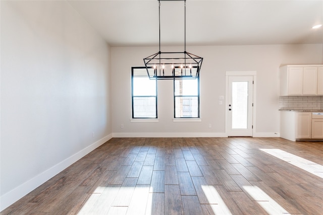 unfurnished dining area with a notable chandelier and hardwood / wood-style floors