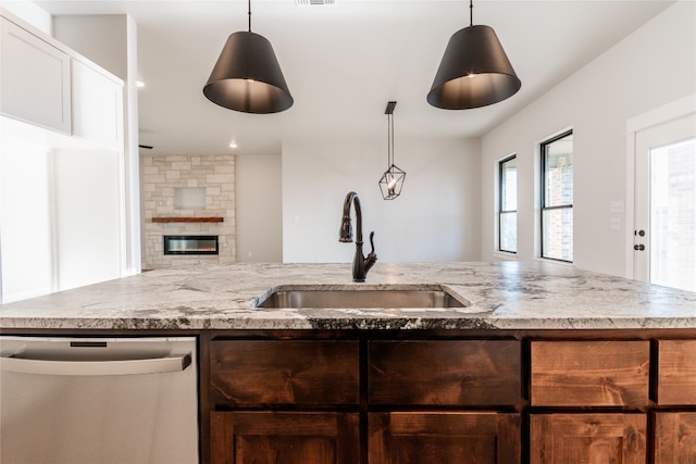 kitchen with hanging light fixtures, a fireplace, sink, and dishwasher