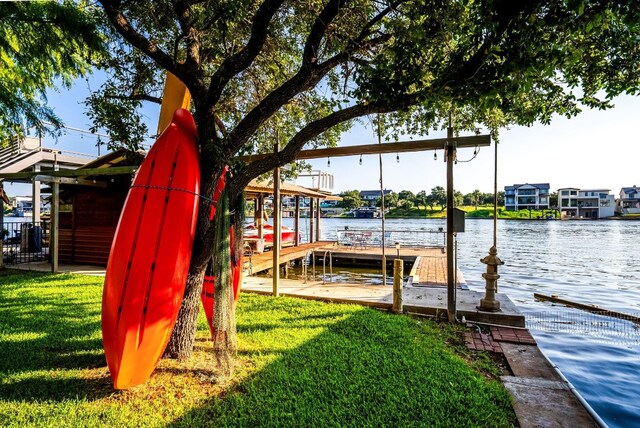 view of dock with a yard and a water view