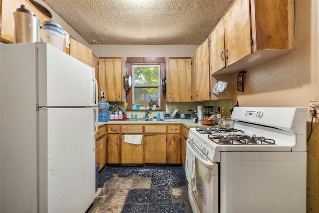 kitchen with sink, dark tile patterned flooring, a textured ceiling, and white appliances