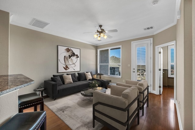 living room featuring crown molding, dark wood-type flooring, and ceiling fan