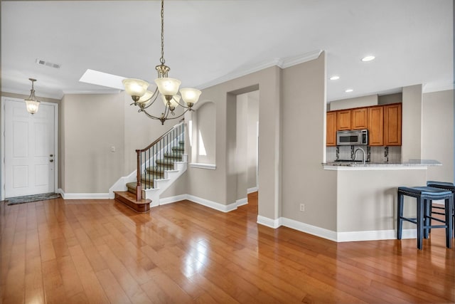 interior space featuring crown molding, a kitchen breakfast bar, hanging light fixtures, and light hardwood / wood-style floors