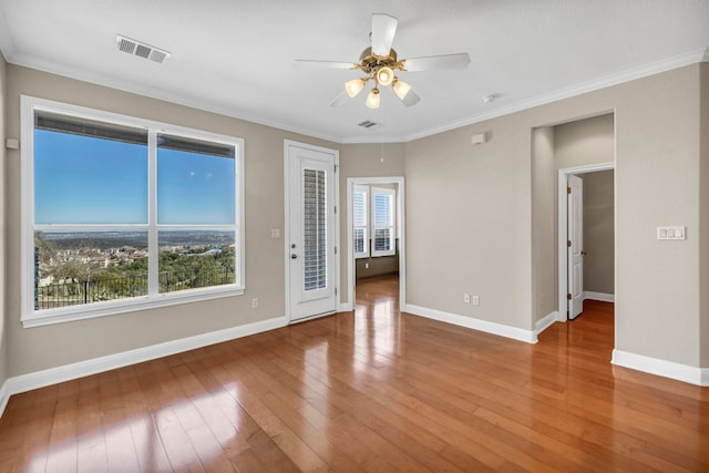 unfurnished room featuring ornamental molding, wood-type flooring, and a wealth of natural light