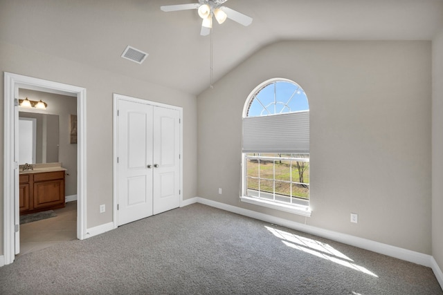 unfurnished bedroom with vaulted ceiling, multiple windows, and light carpet