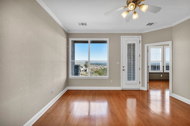 empty room with ornamental molding, hardwood / wood-style floors, and ceiling fan