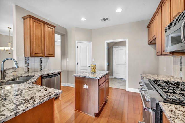 kitchen featuring light hardwood / wood-style flooring, appliances with stainless steel finishes, a center island, backsplash, and sink