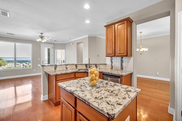 kitchen with tasteful backsplash, ceiling fan with notable chandelier, dishwasher, light hardwood / wood-style flooring, and sink