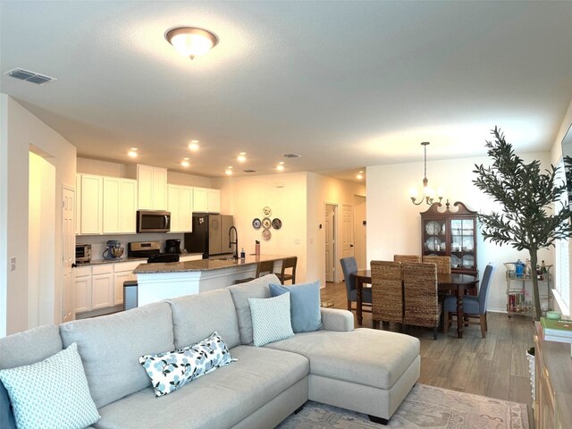 living room with light wood-type flooring, sink, and an inviting chandelier