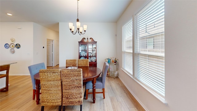 dining room with light wood-type flooring, a chandelier, and plenty of natural light