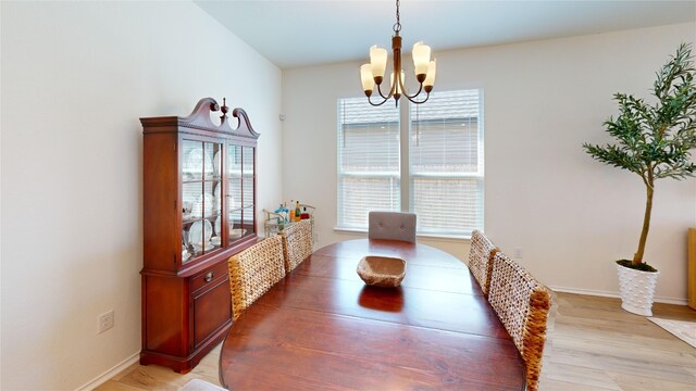 dining room with light wood-type flooring and an inviting chandelier