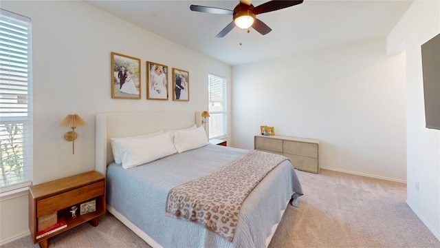 bedroom with light colored carpet, ceiling fan, and multiple windows