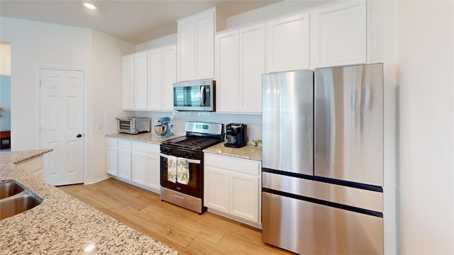 kitchen featuring light hardwood / wood-style flooring, stainless steel appliances, light stone counters, and white cabinetry