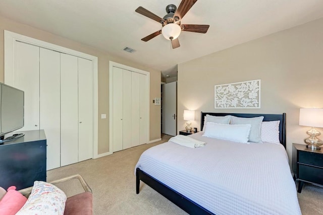 carpeted bedroom featuring two closets and ceiling fan