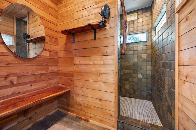 bathroom with a tile shower and wooden walls