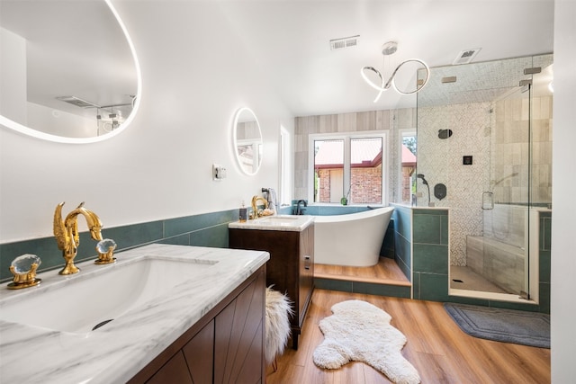 9000 Bear Creek Dr, Austin, TX 78737 - bathroom with a shower stall, wood finished floors, a freestanding bath, two vanities, and tile walls