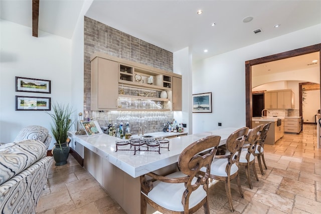 kitchen with tasteful backsplash, a breakfast bar area, light brown cabinetry, and light tile patterned floors