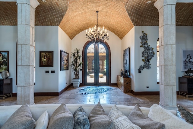 tiled entrance foyer featuring high vaulted ceiling, ornate columns, a chandelier, and brick ceiling