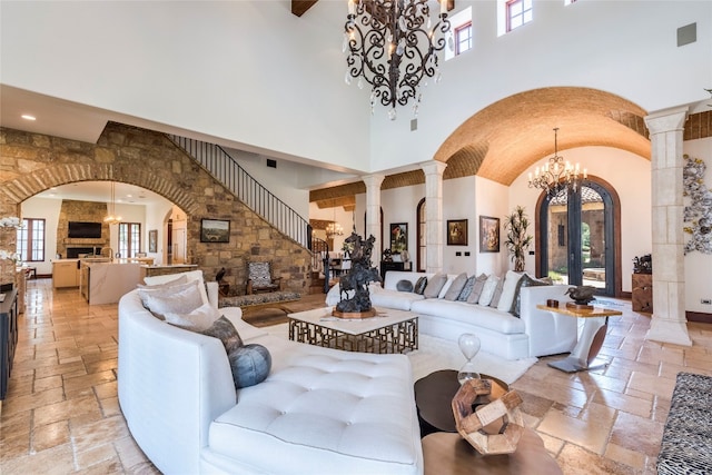 living room featuring decorative columns, light tile patterned floors, high vaulted ceiling, and a chandelier