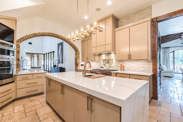 kitchen featuring light tile patterned flooring, pendant lighting, a center island with sink, and decorative backsplash